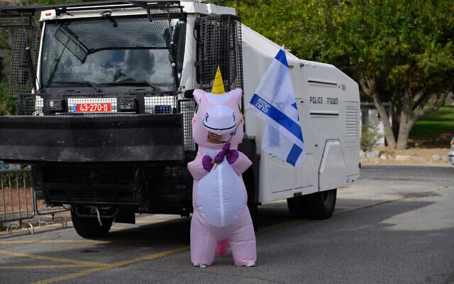 An anti-judicial overhaul activist stands in front of a police water cannon near a hotel in the Golan Heights moshav of Neve Ativ, where Prime Minister Benjamin Netanyahu and his wife Sara are planning to vacation, October 1, 2023. (Ayal Margolin/FLASH90) An anti-judicial overhaul activist stands in front of a police water cannon near a hotel in the Golan Heights moshav of Neve Ativ, where Prime Minister Benjamin Netanyahu and his wife Sara are planning to vacation, October 1, 2023. (Ayal Margolin/FLASH90)