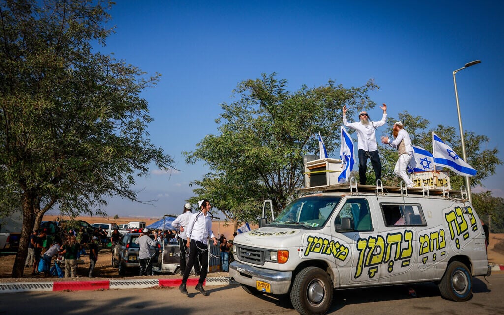 Ultra-Orthodox men dance on a car while Israelis hand out food to Israeli soldiers near the border with the Gaza Strip, October 11, 2023. (Chaim Goldberg/ Flash90)