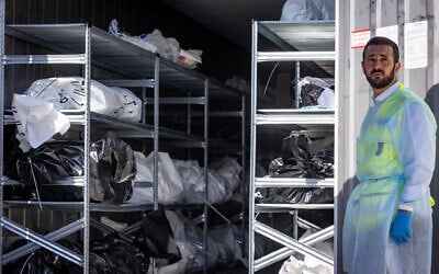 A Zaka volunteer stands in front of a refrigerator truck, serving as a temporary mortuary for victims of Hamas' October 7 attack, at the Military Rabbinate's headquarters in Ramle, October 13, 2023. (Nati Shohat/Flash90)