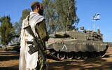 An Israeli soldier with a prayer shawl seen during a morning prayer near his tank near the border with Lebanon, northern Israel, October 25, 2023. (Michael Giladi/Flash90)