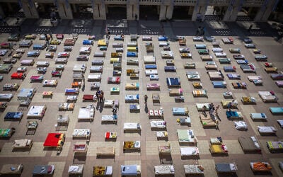 People walk between hundreds of beds corresponding to the number of Israelis abducted by the terrorist organization Hamas in the Gaza Strip, outside Jerusalem City Hall on October 30, 2023. (Yonatan Sindel/Flash90)