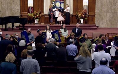 Illustrative: Clergy and congregants sing 'Hatikvah,' Israel's national anthem, while holding Torah scrolls during a muted Simchat Torah service at Anshe Emet Synagogue in Chicago, October 7, 2023. (Screenshot via JTA)