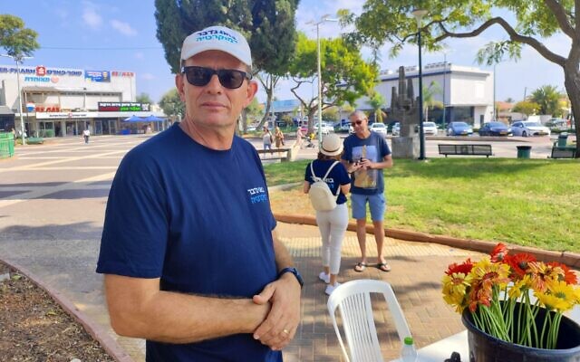 Bo Nidaber activist Eytan Cohen-Munwes waits, while founder Daphne Haim-Langford engages with a passerby in the background, in Or Akiva, on September 22, 2023. (Gavriel Fiske/Times of Israel)