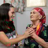 Yael Eckstein holding hands of an elderly woman, Netta, in Israel. (Credit: Olivier Fitoussi)