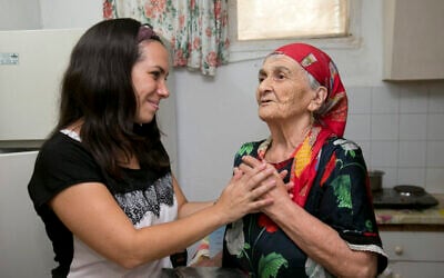 Yael Eckstein holding hands of an elderly woman, Netta, in Israel. (Credit: Olivier Fitoussi)