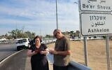 Rachel and Boaz Sadeh study their phones as they wait for a sign of life from their son, Ziv, on October 7, 2023, near Ofakim. (Canaan Lidor/Times of Israel)