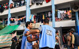 Workers of the United Nations Relief and Works Agency for Palestine Refugees (UNRWA) agency talk together in the playground of an UNRWA-run school that has been converted into a shelter for displaced Palestinians in Khan Younis in the southern Gaza Strip on October 25, 2023. (Mahmud Hams/AFP)