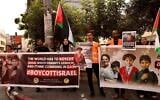 Palestinians holds posters asking for the boycotting of Israeli products during a rally in the West Bank city of Hebron on October 28, 2023. (HAZEM BADER / AFP)