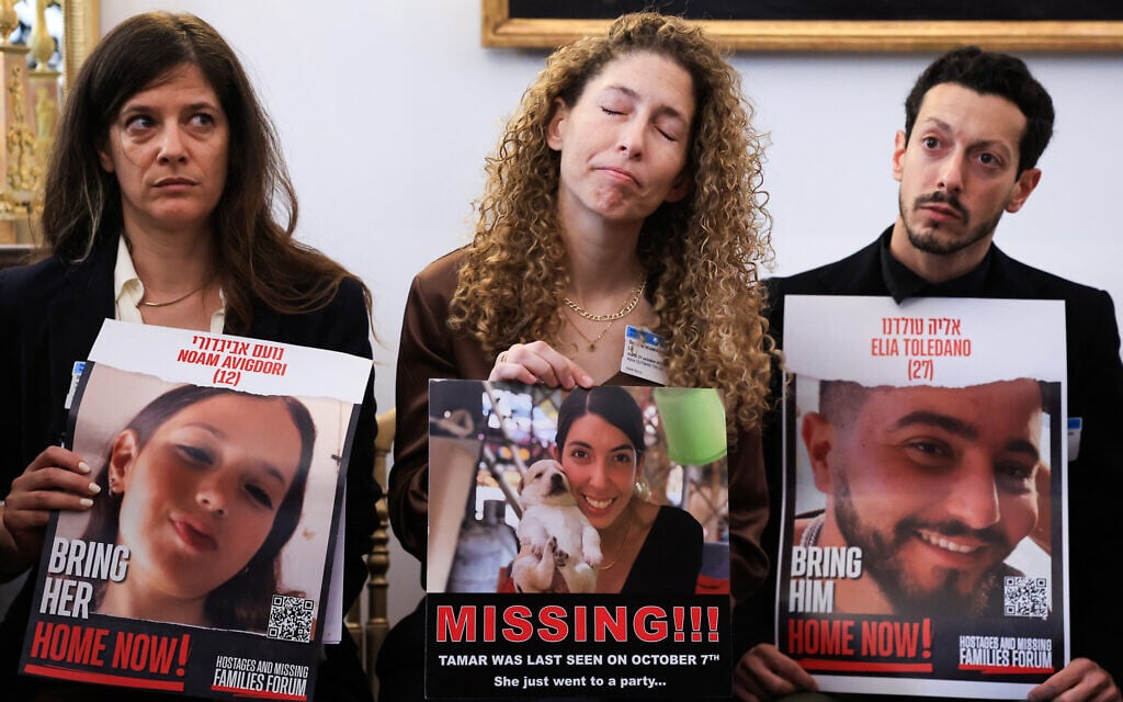 Relatives and acquaintances hold pictures of hostages and missing persons during a meeting on behalf of hostages abducted from Israel by terrorists on October 7, 2023, at the French National Assembly, in Paris, on October 31, 2023. (Photo by Emmanuel Dunand / AFP)