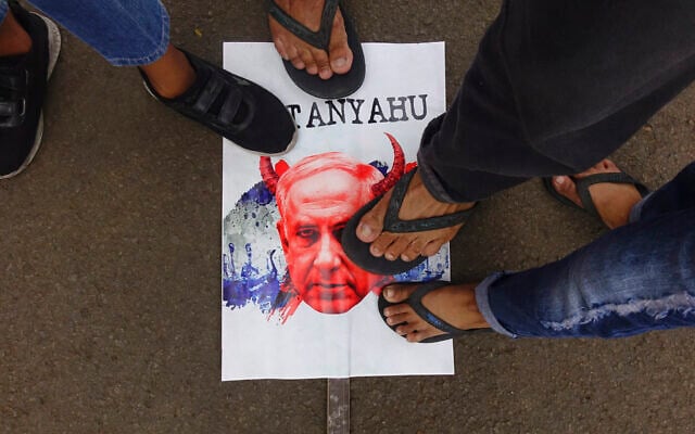 People step on a caricature of Prime Minister Benjamin Netanyahu during a rally to show their solidarity with Palestinians at the National Monument in Jakarta on November 5, 2023. (Photo by Azwar IPANK / AFP)