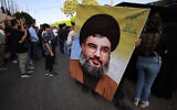 A person holds a picture of Hezbollah chief Hassan Nasrallah during the funeral of a Hezbollah member who was killed in southern Lebanon in cross-border fire with Israeli troops, during his funeral in a south Beirut suburb, on November 6, 2023. (Ahmad Al-Rubaye/AFP)
