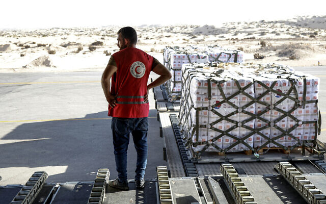 An Egyptian Red Crescent member stands next to a shipment of humanitarian aid bound for the Gaza Strip unloaded off a Qatar Emiri Air Force C-17 Globemaster III military transport aircraft after landing at Arish International Airport in North Sinai province in northeastern Egypt on November 9, 2023 (Karim JAAFAR / AFP) An Egyptian Red Crescent member stands next to a shipment of humanitarian aid bound for the Gaza Strip unloaded off a Qatar Emiri Air Force C-17 Globemaster III military transport aircraft after landing at Arish International Airport in North Sinai province in northeastern Egypt on November 9, 2023 (Karim JAAFAR / AFP)