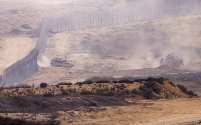 An Israeli bulldozer and a battle tank cross a barbed wire fence at a position along the border between the Gaza Strip and southern Israel on November 12, 2023, (Kenzo TRIBOUILLARD / AFP) An Israeli bulldozer and a battle tank cross a barbed wire fence at a position along the border between the Gaza Strip and southern Israel on November 12, 2023, (Kenzo TRIBOUILLARD / AFP)