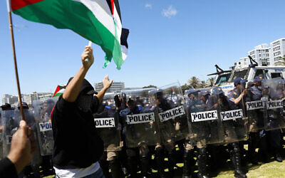 Cape Town Metro Police Department (CTMPD) officers line up as a man waves a Palestinian flag in Cape Town on November 12, 2023, after pro-Israeli supporters were chased away by an opposing group as they were gathering. (Photo by GIANLUIGI GUERCIA / AFP)
