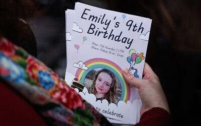 A woman holds leaflets picturing Irish-Israeli girl Emily Hand held hostage by Palestinian terror group Hamas in Gaza during a gathering for her 9th birthday outside the office of Save The Children International in London on November 17, 2023. (Daniel Leal/AFP)