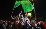 Released Palestinian security prisoners (wearing gray) who were released from Israel's Ofer military facility in exchange for Israeli hostages freed by Hamas in Gaza, wave flags and chant slogans as they are paraded in Beitunia in the West Bank on November 24, 2023. (Jaafar Ashtiyeh/AFP)