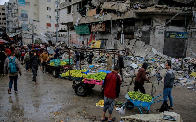 Palestinians sell vegetables in front of a destroyed building in Gaza City on November 27, 2023. (Omar El-Qattaa / AFP) Palestinians sell vegetables in front of a destroyed building in Gaza City on November 27, 2023. (Omar El-Qattaa / AFP)