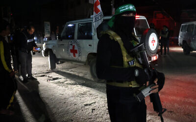 Illustrative: A Hamas terrorist stands guard as a Red Cross vehicle transports newly released hostages in Rafah, in the southern Gaza Strip on November 28, 2023. (AFP)