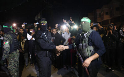 Hamas and Islamic Jihad terrorists shake hands after handing over hostages to the Red Cross in Rafah, in the southern Gaza Strip, on November 28, 2023. (AFP)