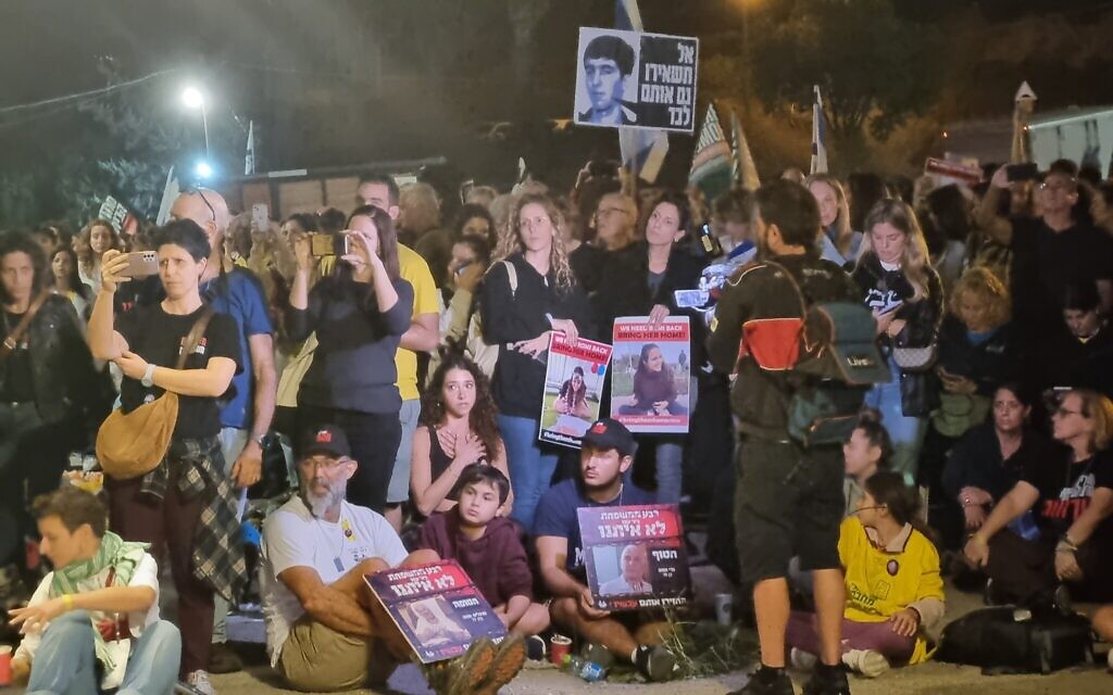 Family members hold  photos of their kidnapped relatives for the media following a ceremony at their campsite adjacent to  the Armored Corps Memorial Site at Latrun on November 16, 2023. (Bernard Dichek/Times of Israel)