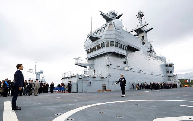 French President Emmanuel Macron, left, stands at attention on the deck of the amphibious helicopter carrier Dixmude docked in the French Navy base of Toulon, southern France, Wednesday, Nov. 9, 2022. (Eric Gaillard, Pool via AP)