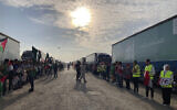 Volunteers stand in front of trucks carrying humanitarian aid to Palestinians at the Rafah border crossing between Egypt and Gaza Strip, in Rafah, Egypt, October 31, 2023. (Ahmed Hatem/AP)