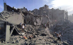 Palestinians inspect the damage of buildings destroyed after Israeli airstrikes on the Jabaliya refugee camp on the outskirts of Gaza City, October 31, 2023. The IDF said the airstrikes were part of 'a wide-scale strike' on Hamas operatives and infrastructure belonging to the terror group’s Central Jabaliya Battalion and that the buildings collapsed when Hamas tunnels were targeted. (Abdul Qader Sabbah/AP)
