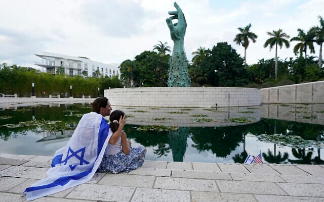 Draped in an Israeli flag, Elinor Ben David, left, hugs her daughter Liel Abissidan, 8, as they wait for a rally in support of Israel to start, at the Holocaust Memorial Miami Beach, October 10, 2023, in Miami Beach, Florida. (AP/Wilfredo Lee) Draped in an Israeli flag, Elinor Ben David, left, hugs her daughter Liel Abissidan, 8, as they wait for a rally in support of Israel to start, at the Holocaust Memorial Miami Beach, October 10, 2023, in Miami Beach, Florida. (AP/Wilfredo Lee)