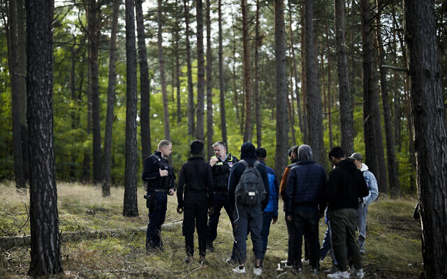 A federal police officer speaks into his radio as he and a colleague track down a group of migrants who have illegally crossed the border from Poland into Germany, while on patrol in a forest near Forst, southeast of Berlin, Germany, on October 11, 2023. (AP Photo/Markus Schreiber)