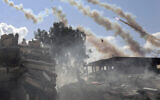 Rockets are fired from the Gaza Strip toward Israel over destroyed buildings, October 19, 2023. (AP Photo/Mohammed Dahman)