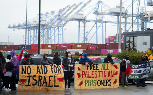 Protesters hold up large wooden signs as they block the main Port of Tacoma entrance to delay the loading of the Cape Orlando vessel, Nov. 6, 2023, in Tacoma, Washington. (AP Photo/Lindsey Wasson) Protesters hold up large wooden signs as they block the main Port of Tacoma entrance to delay the loading of the Cape Orlando vessel, Nov. 6, 2023, in Tacoma, Washington. (AP Photo/Lindsey Wasson)