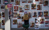 A woman writes on a photo of people held hostage in Gaza at an installation in Tel Aviv, Nov. 7, 2023. (AP Photo/Ariel Schalit)