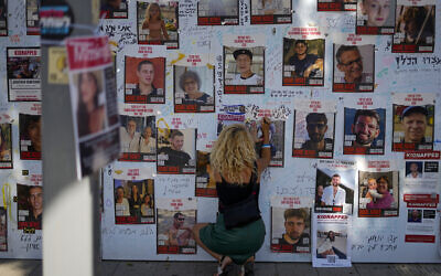A woman writes on a photo of people held hostage in Gaza at an installation in Tel Aviv, Nov. 7, 2023. (AP Photo/Ariel Schalit) A woman writes on a photo of people held hostage in Gaza at an installation in Tel Aviv, Nov. 7, 2023. (AP Photo/Ariel Schalit)