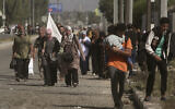 A woman carries a white flag with a group of Palestinians fleeing Gaza City to the southern Gaza Strip on Salah al-Din street in Bureij, November 7, 2023. (AP Photo/Mohammed Dahman)