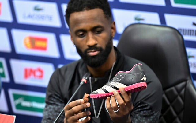 Israel team captain Eli Dasa shows a shoe of a kidnapped Israeli boy during a press conference, before a training session for the Euro 2024 group I qualifying soccer match between Israel and Switzerland at the Pancho Arena in Felcsút, Hungary, November 14, 2023. The shoe belongs to 8-year-old Nave Shoham, who along with seven relatives was taken captive in the Hamas terror group's October 7 onslaught.(AP Photo/Denes Erdos) Israel team captain Eli Dasa shows a shoe of a kidnapped Israeli boy during a press conference, before a training session for the Euro 2024 group I qualifying soccer match between Israel and Switzerland at the Pancho Arena in Felcsút, Hungary, November 14, 2023. The shoe belongs to 8-year-old Nave Shoham, who along with seven relatives was taken captive in the Hamas terror group's October 7 onslaught.(AP Photo/Denes Erdos)