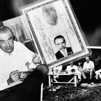 A federal police agent holds two photos and the identity card found in the house in which the man believed to be Nazi war criminal Josef Mengele lived, June 7, 1985. Photo on left shows Mengele eating. Photo on right shows Mengele during a picnic with friends and in the middle is the identity card. (AP Photo)