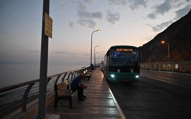 A bus driver sits outside his empty vehicle in the deserted border crossing in Eilat, Israel into Egypt on October 31, 2023. (Canaan Lidor/Times of Israel) A bus driver sits outside his empty vehicle in the deserted border crossing in Eilat, Israel into Egypt on October 31, 2023. (Canaan Lidor/Times of Israel)