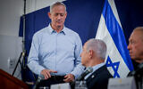 Then-Cabinet Minister Benny Gantz (standing), Prime Minister Benjamin Netanyahu (center), and Defense Minister Yoav Gallant, at a press conference at the Defense Ministry headquarters in Tel Aviv, November 22, 2023. (Chaim Goldberg/Flash90)