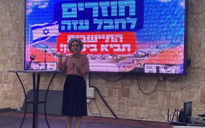 Otzma Yehudit MK Limor Son Har-Melech addresses a crowd of hundreds of activists on the backdrop of a sign that says, 'Returning to Gaza Strip, Settlements Bring Security,' in Ashdod on November 22, 2023. (Mati Wagner/Times of Israel)