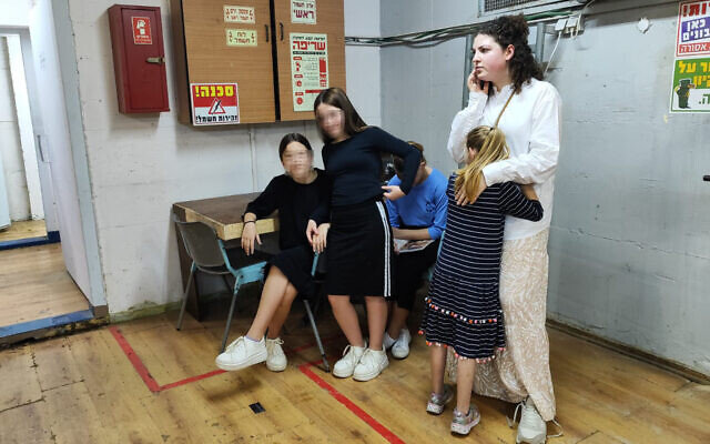 An Alumim foster student receives a hug from a teacher while waiting in a bomb shelter in the Or Simcha youth village, in Kfar Chabad, central Israel, October 26, 2023. (Gavriel Fiske/Times of Israel)