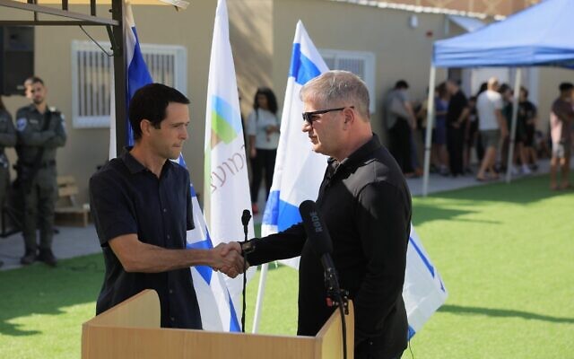 Education Minister Yoav Kisch, right, shakes hands with Amichai Has, education director of the Eshkol Regional Council, at the opening of a new school for Gaza area evacuees near the Dead Sea, on November 8, 2023. (courtesy Education Ministry spokesman's office)