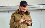 Yanki Deri checks his phone shortly after enlisting to the Israel Defense Forces near Tel Aviv, Israel on November 8, 2023. (Courtesy)