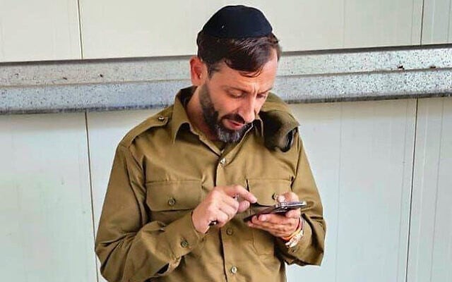 Yanki Deri checks his phone shortly after enlisting to the Israel Defense Forces near Tel Aviv, Israel on November 8, 2023. (Courtesy) Yanki Deri checks his phone shortly after enlisting to the Israel Defense Forces near Tel Aviv, Israel on November 8, 2023. (Courtesy)