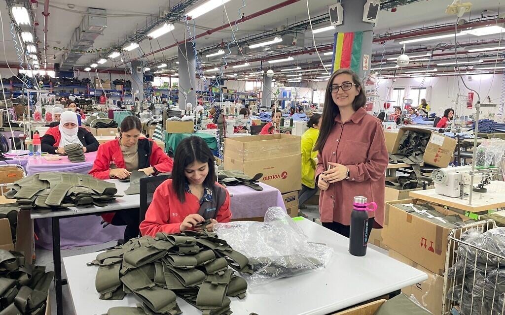 Hotaf Kablan (standing, right), responsible for production, poses next to some of the 250 Druze seamstresses at the Maquette Textil factory in Beit Jann, November 1, 2023. (Sue Surkes/Times of Israel)