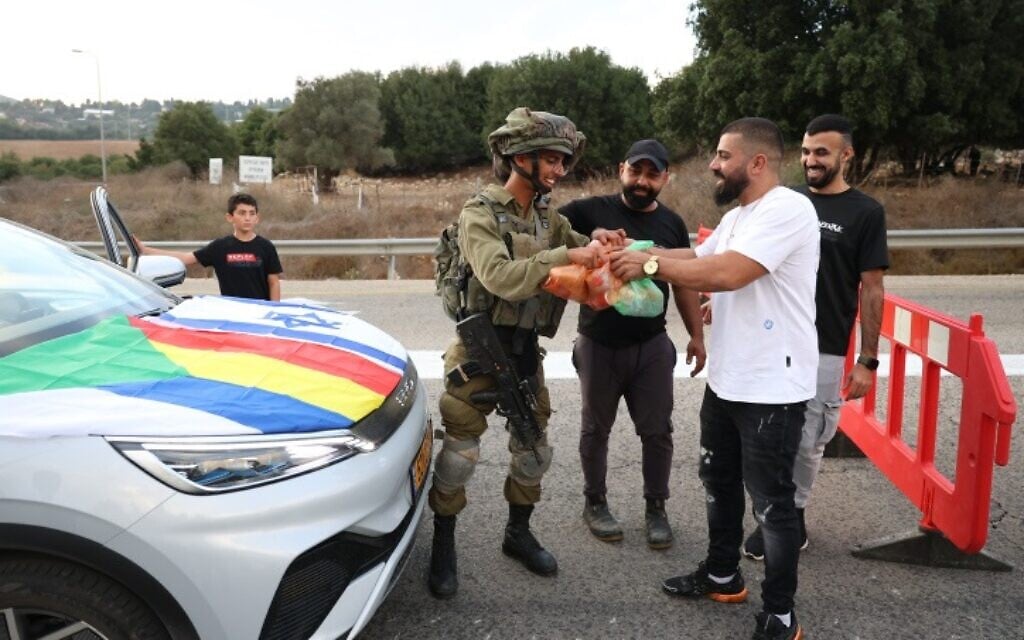 Druze residents hand out food to Israeli soldiers guarding a road near the Israeli border with Lebanon, on October 9, 2023. (David Cohen/Flash90)