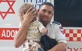 A Magen David Adom medic with a toddler found walking alone on Dizengoff Street, November 20, 2023. (Magen David Adom)
