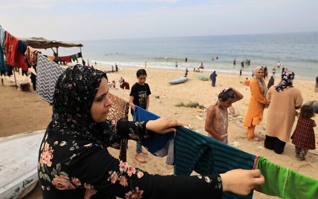 A Palestinian woman hangs laundry washed using sea water due to the lack of fresh water and electricity, along the beach in Deir el-Balah in the southern Gaza Strip on October 29, 2023. (Photo by Mahmud HAMS / AFP) A Palestinian woman hangs laundry washed using sea water due to the lack of fresh water and electricity, along the beach in Deir el-Balah in the southern Gaza Strip on October 29, 2023. (Photo by Mahmud HAMS / AFP)