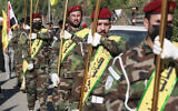 Fighters lift flags of Iraq and paramilitary groups, including al-Nujaba and Kataib Hezbollah, during a funeral in Baghdad on December 4, 2023. (AHMAD AL-RUBAYE / AFP)