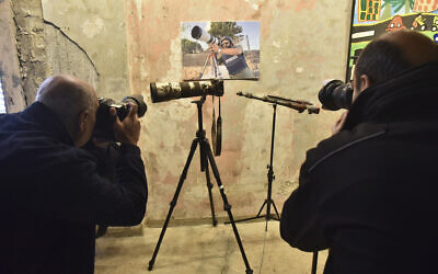 Photographers take pictures of the damaged camera of late Reuters visuals journalist Issam Abdallah (portrait) during a joint press conference by Human Rights Watch and Amnesty International in Beirut on December 7, 2023. (AFP)