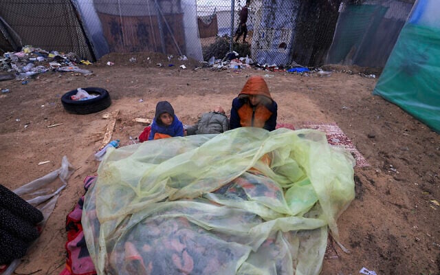 Young Palestinians sit outside on mattresses covered with plastic at a camp for displaced people in Rafah, in the southern Gaza Strip on December 13, 2023, during the Israel-Hamas war. (Mahmud HAMS / AFP)